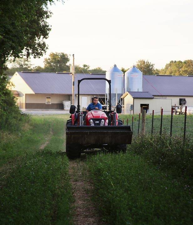 Burkholder child driving a tractor along a pasture fence row